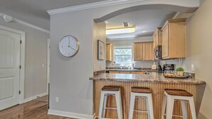 A kitchen with wooden cabinets, a granite countertop, and three bar stools. - Charming Springdale Townhome ~ 5 Mi to Dtwn! (Springdale)