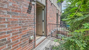 A brick building with a wooden deck and a metal railing. - Charming Springdale Townhome ~ 5 Mi to Dtwn! (Springdale)