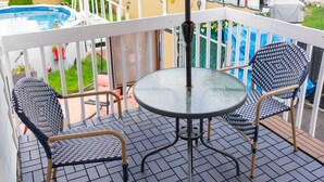 Une terrasse couverte avec une piscine, deux chaises et une table.