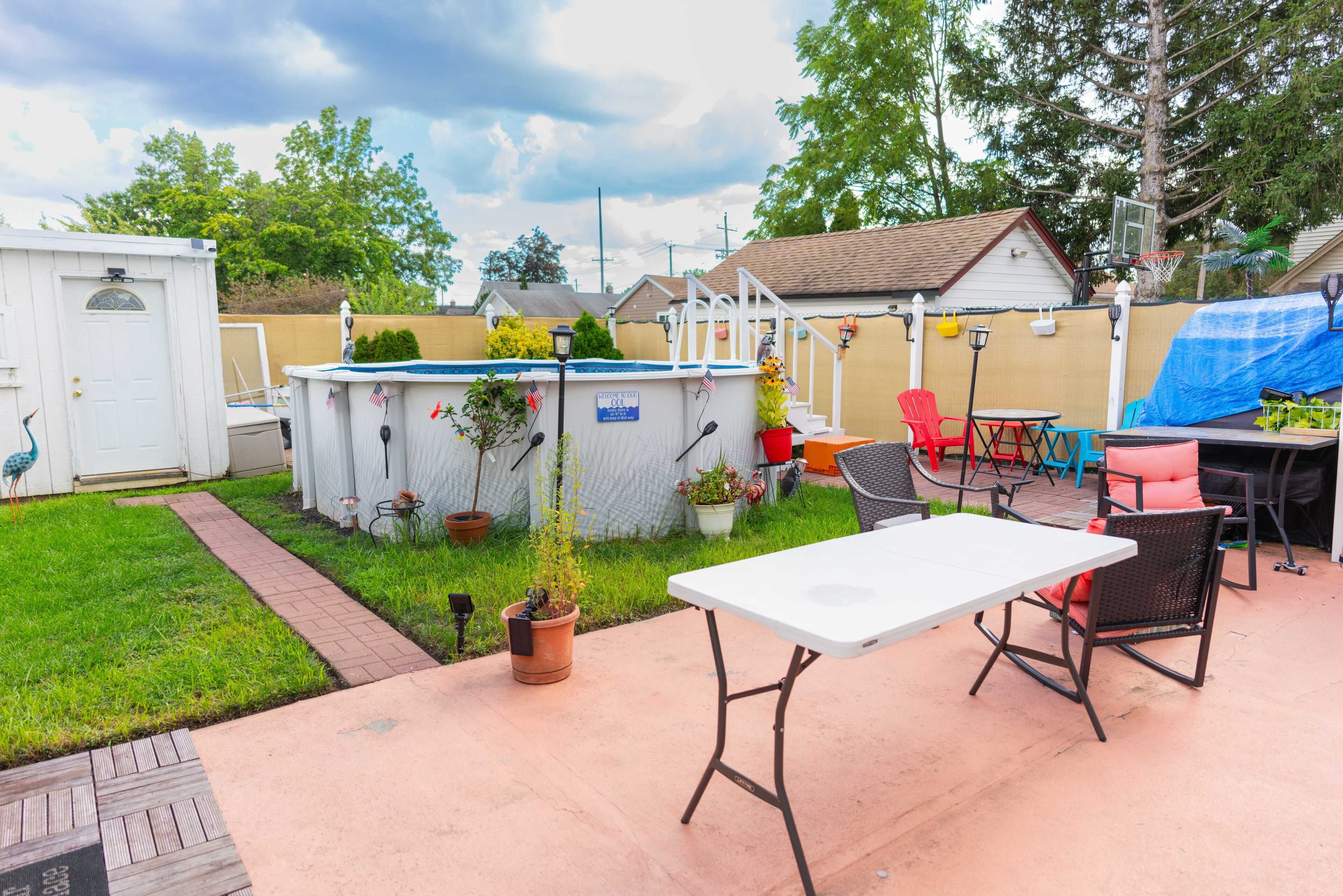 A backyard with a pool, patio furniture, and a small shed.