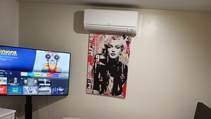 Une chambre à coucher avec un lit, une télévision et un climatiseur.