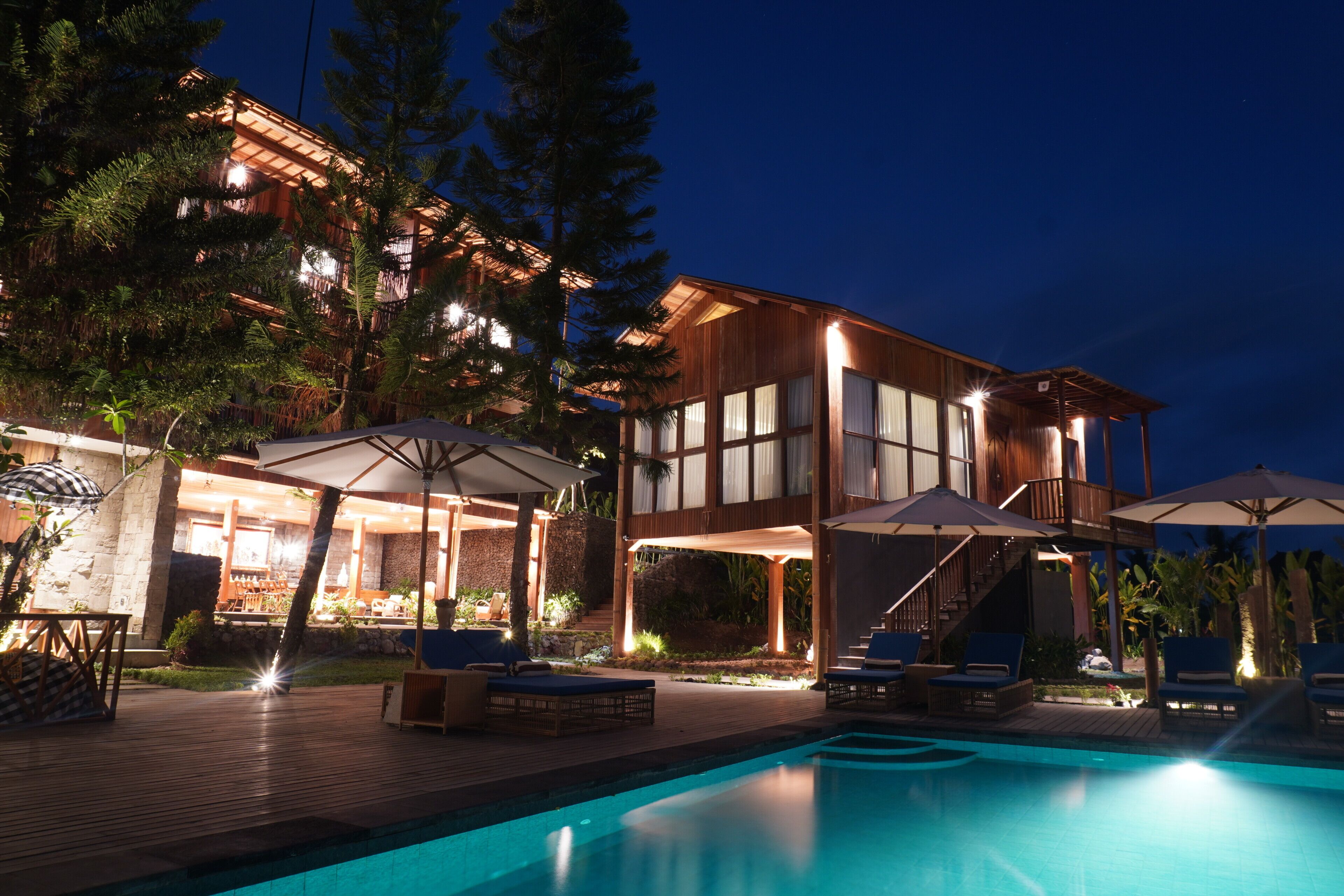 Un resort moderno con piscina, zona de estar exterior y un edificio bien iluminado.