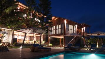 Un resort moderno con piscina, zona de estar exterior y un edificio bien iluminado.