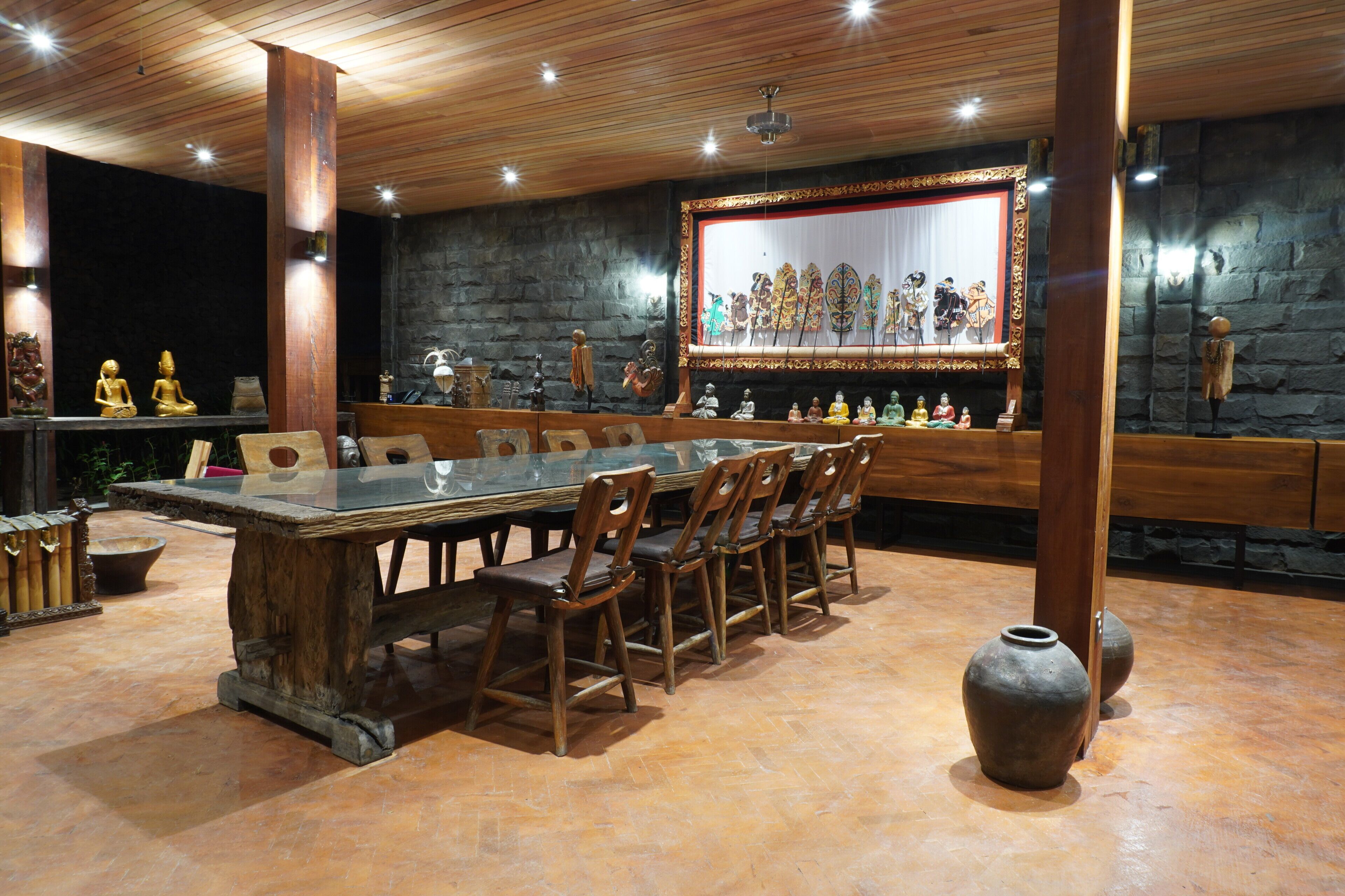 Un comedor con una larga mesa de madera y sillas, rodeado de paredes de piedra y vigas de madera.