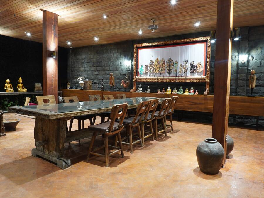 Un comedor con una larga mesa de madera y sillas, rodeado de paredes de piedra y vigas de madera.