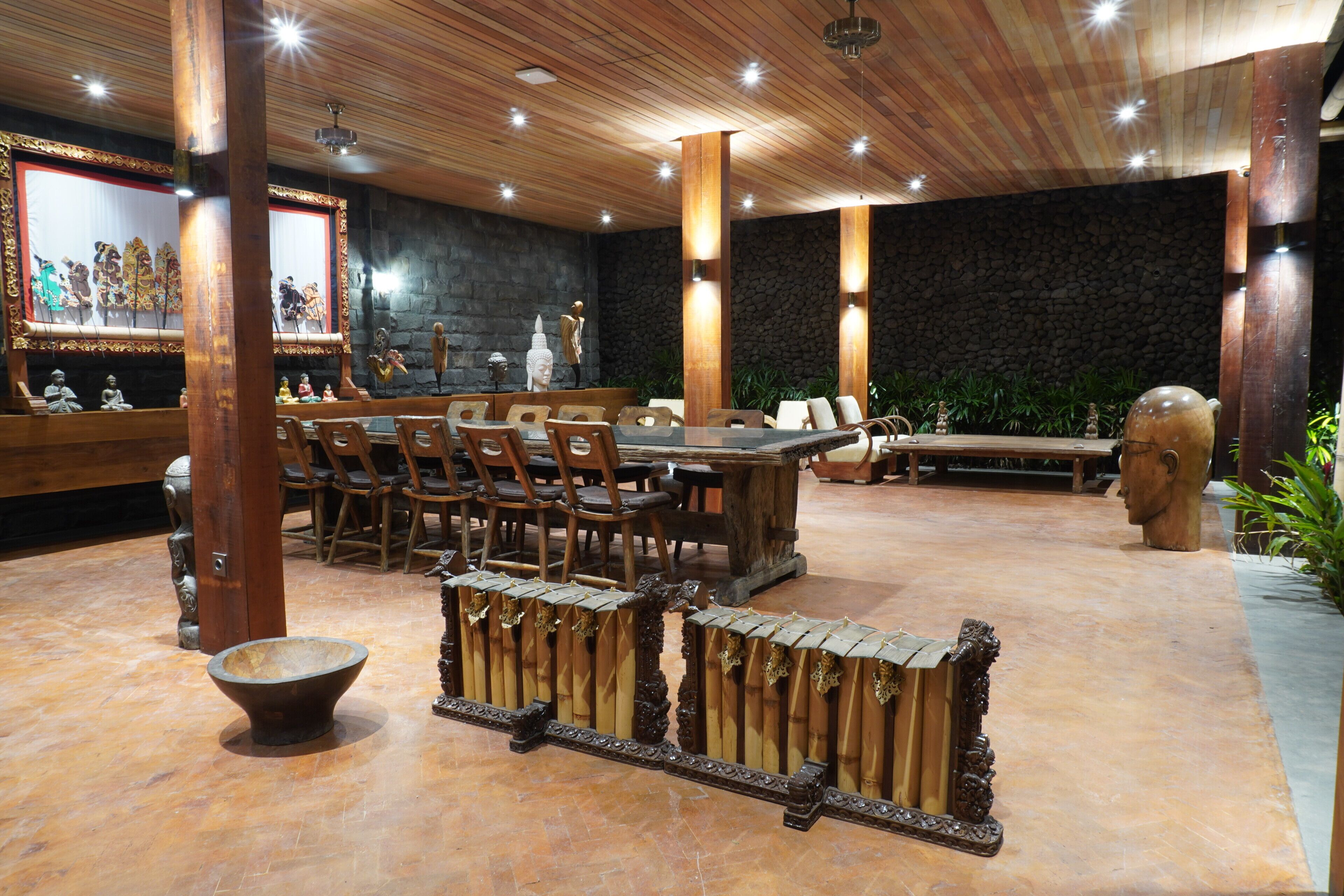 A traditional-style room with wooden furniture, stone walls, and a large Buddha statue.