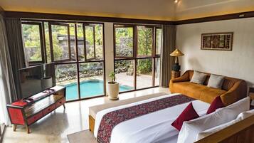 A bedroom with a large bed, a sofa, a TV, and a view of a swimming pool.