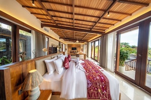 A spacious bedroom with a large bed, wooden ceiling beams, and a view of the outdoors. - Kropak Sidemen (Sidemen)