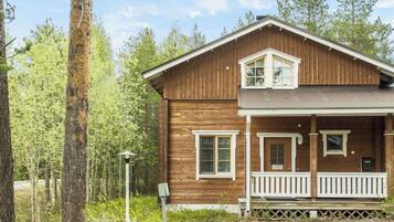 Una baita in legno a due piani con un portico, un piccolo balcone e una cassetta delle lettere.