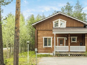 En toetages træhytte med veranda, en lille balkon og en postkasse.