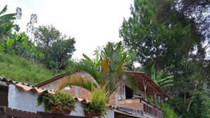 Ein zweistöckiges Haus mit hölzernem Tor, einer kleinen Veranda und einem Balkon.