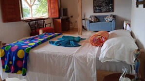 Ein Schlafzimmer mit zwei Betten, einem Fenster mit Holzläden, einem Bild an der Wand und einem Sessel.