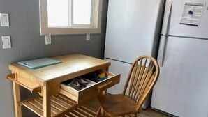 A kitchen with a wooden table, chair, and a refrigerator.