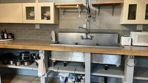 A kitchen with a stainless steel sink, wooden countertop, and cabinets.