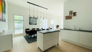 Una cocina moderna con una isla central, armarios blancos e iluminación colgante.