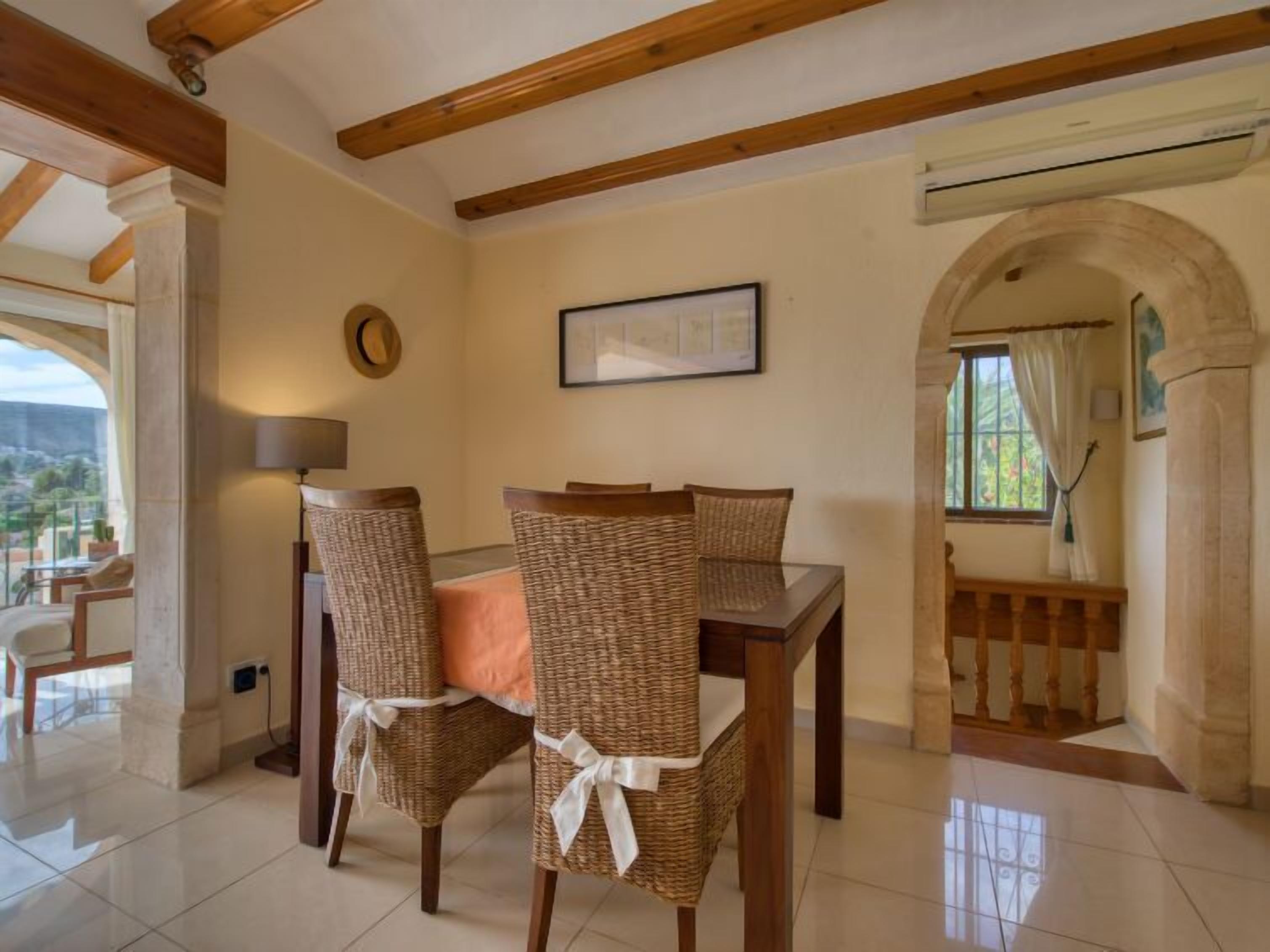 Comedor con sillas de mimbre, una mesa de madera y vistas a un balcón.