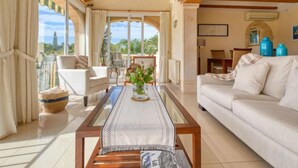 A spacious living room with a balcony, wooden beams, a sofa, a coffee table, and a dining area. - Isabelle by Interhome (Jávea)