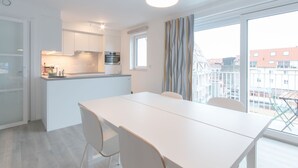 Uma cozinha moderna com armários brancos, forno embutido e janela com vista para a cidade.