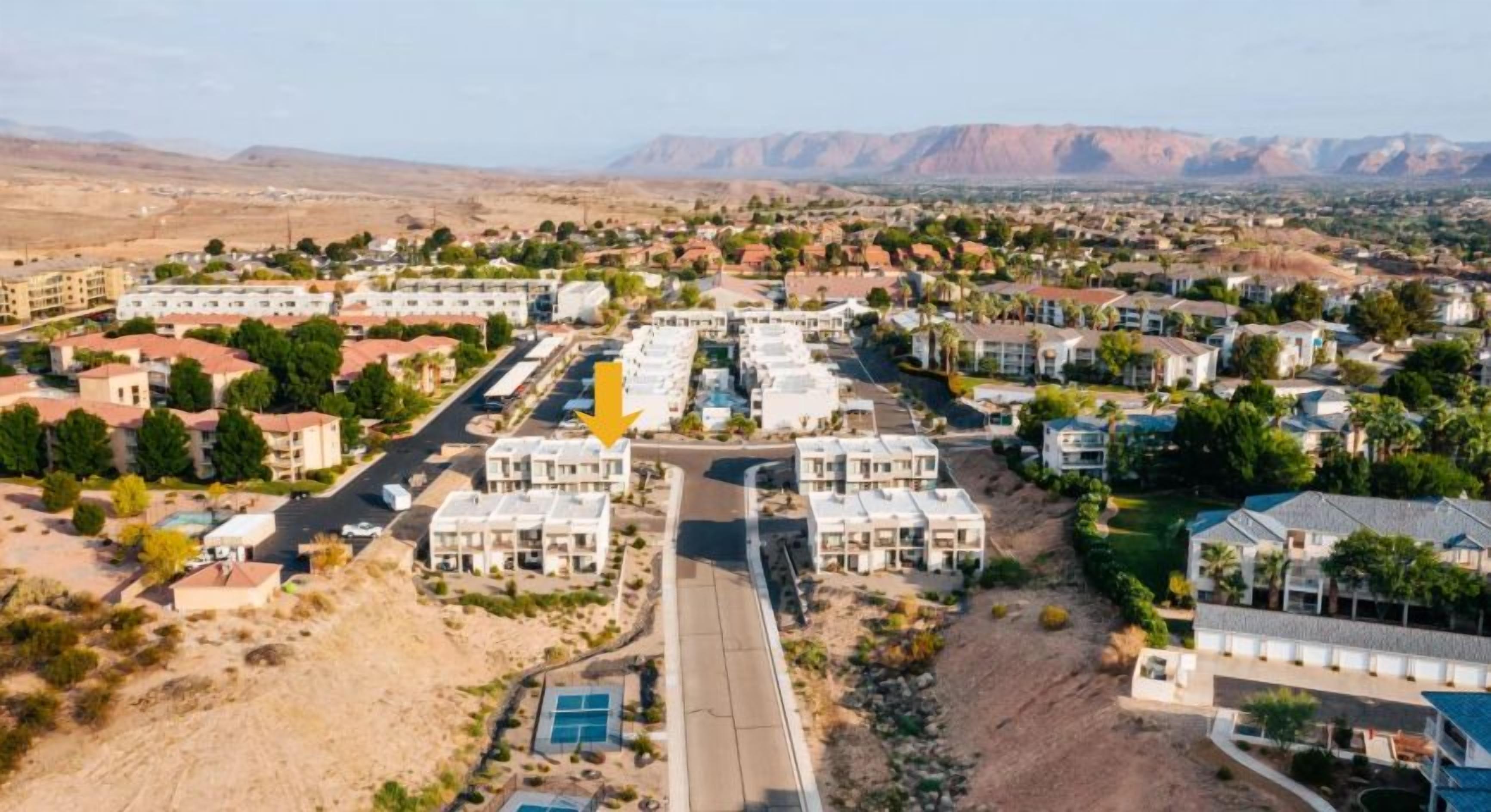 A residential area with multiple apartment buildings, a main road, and a clear view of distant mountains.