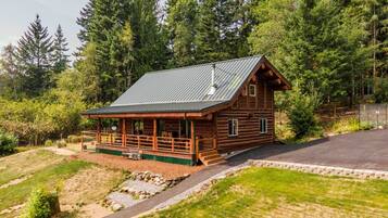 Een vakantiehuisje van hout met een veranda, omringd door een bos.