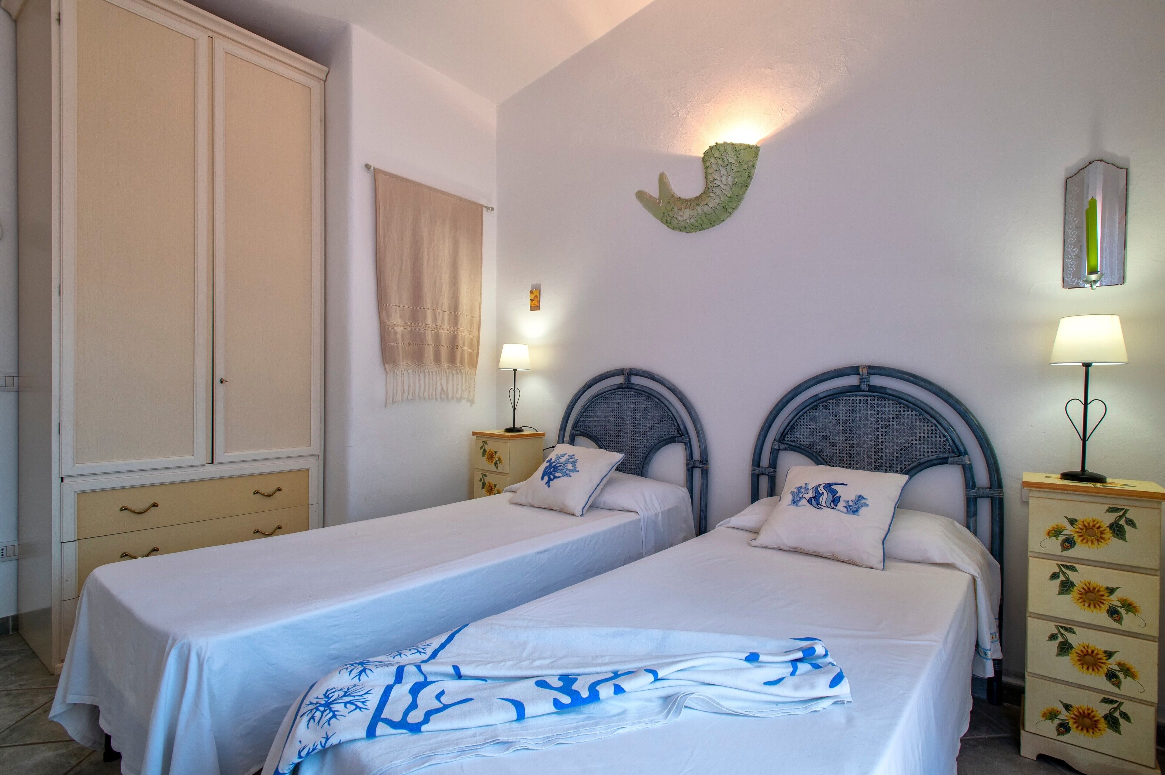 Habitación doble con dos camas, un armario, un espejo y una lámpara de pared.