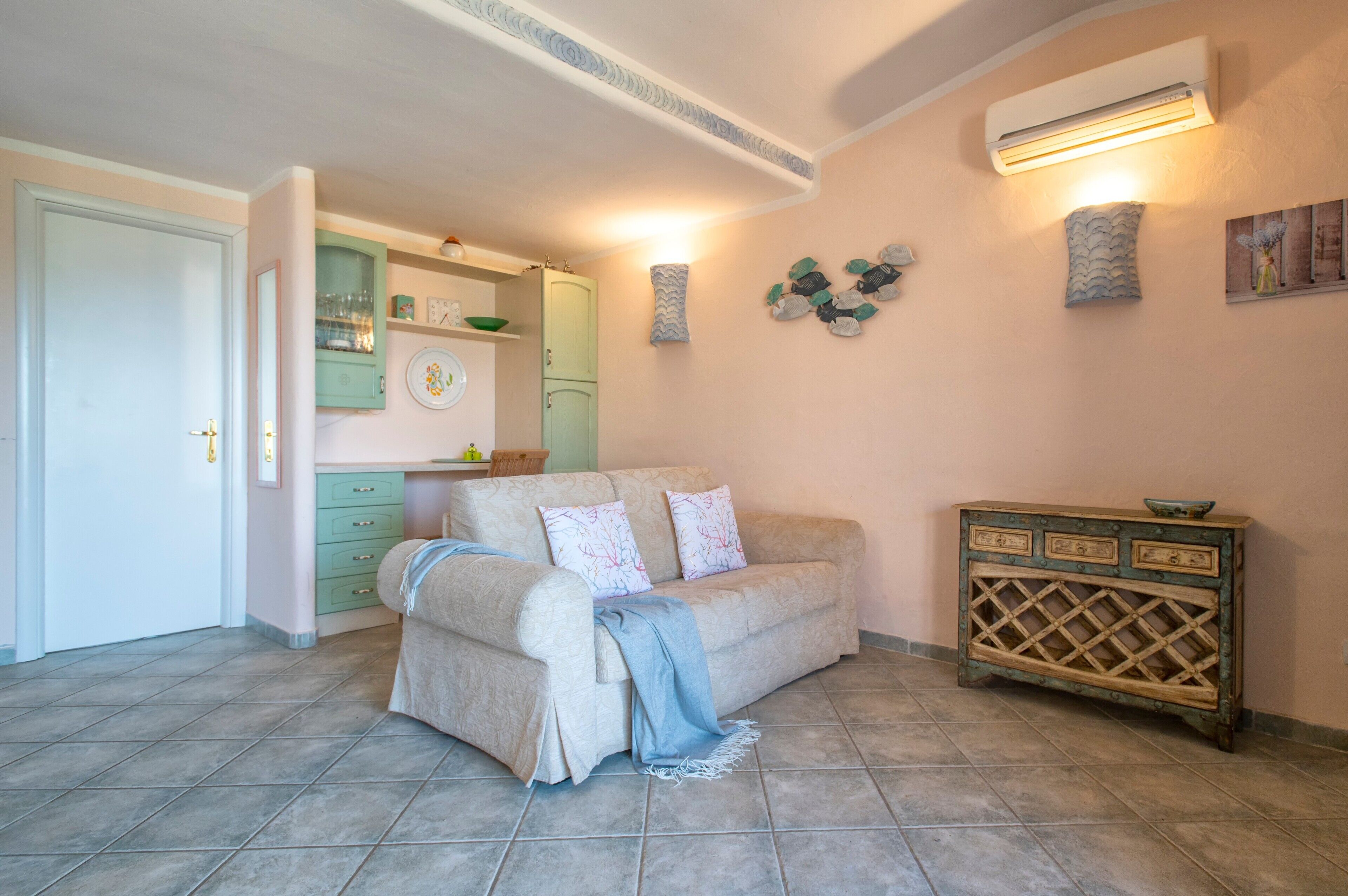 Una sala de estar con un sofá color beige, un aparador verde y una mesita de madera.