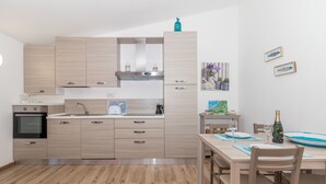 Una cocina moderna con armarios de madera clara, horno empotrado y comedor con mesa y sillas de madera.