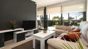 A modern living room with a flat-screen TV, a sofa, and a coffee table. - Luxury Beachfront Apartment (Cambrils)