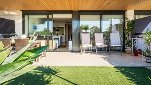A modern house with a patio, outdoor seating, and a well-maintained lawn. - Luxury Beachfront Apartment (Cambrils)