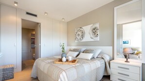 A bedroom with a bed, bedside table, dresser, and artwork on the wall. - Luxury Beachfront Apartment (Cambrils)