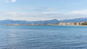 Un paysage urbain côtier avec un port de plaisance, des bâtiments et des montagnes en arrière-plan.