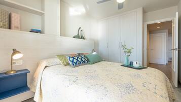 Une chambre à coucher avec un lit, une table de chevet, une lampe et un ventilateur de plafond.