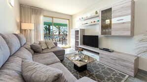 Una sala de estar moderna con sofá, mesa de centro, televisor y estanterías empotradas.