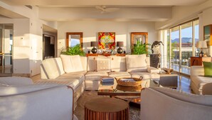 A spacious living room with a large sectional sofa, a coffee table, and a view of the mountains through large windows.
