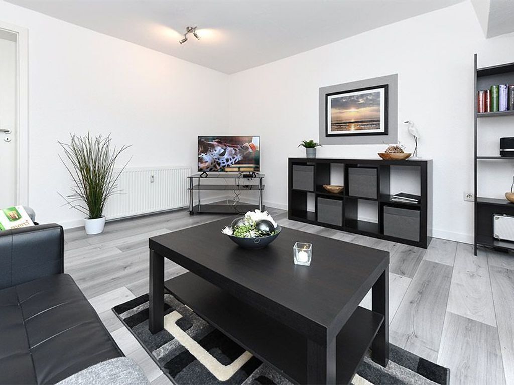 Un salon moderne avec une table basse noire, un téléviseur et une bibliothèque.