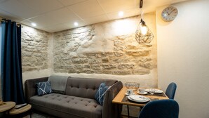 En hyggelig opholdsstue med en stenvæg, en sofa, et spisebord med stole og et ur på væggen.