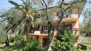 Un immeuble à plusieurs étages doté de balcons, entouré d’une végétation luxuriante et de palmiers.