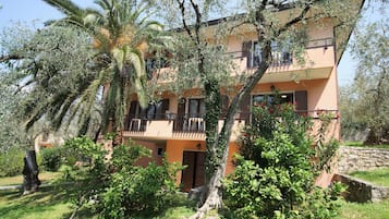 Um edifício de vários andares com varandas, cercado por vegetação exuberante e palmeiras.