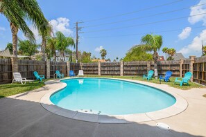 Ein Garten mit Swimmingpool, blauen Stühlen und einem Holzzaun.