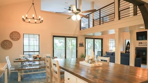 A spacious kitchen with a large island, a dining area with a bench, and a staircase leading to an upper level.