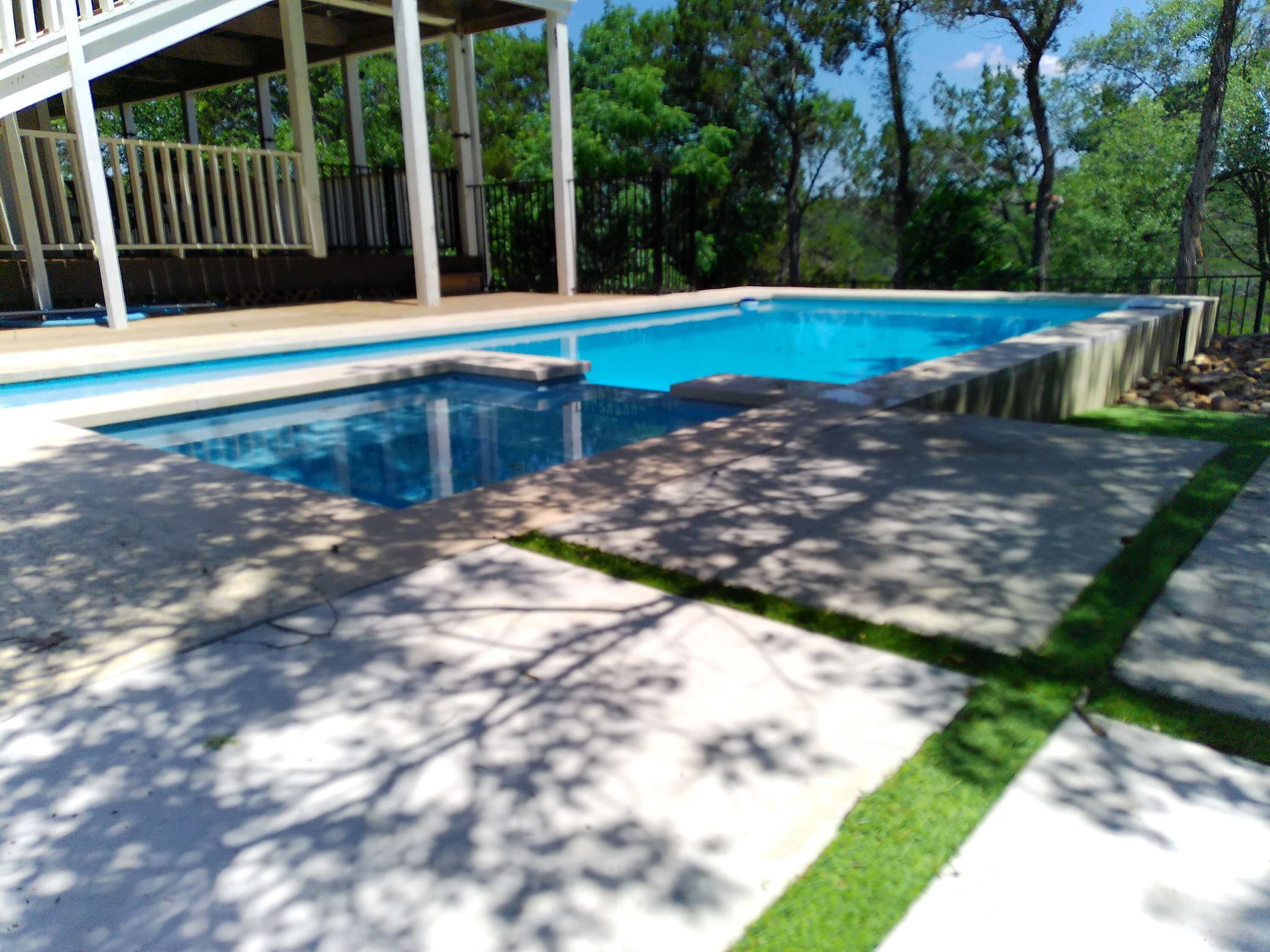 Una piscina con un porche cubierto y un deck de piedra.