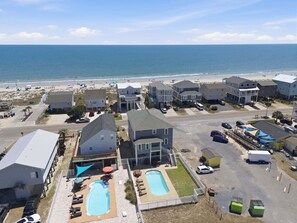Zona residencial costera con casas, una piscina y una playa al fondo.