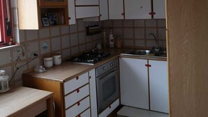 A compact kitchen with white cabinets, a wooden countertop, a stove, an oven, and a sink.