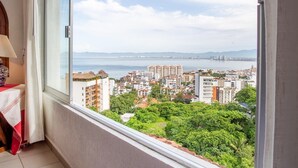 A balcony with a view of a cityscape and greenery.