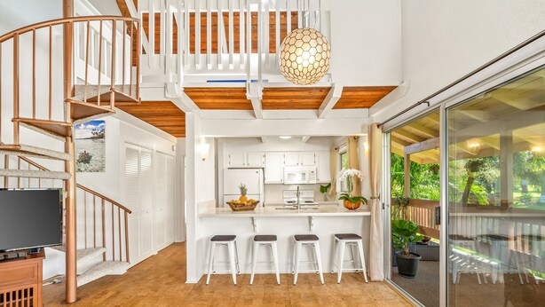 A modern kitchen with a central island, white bar stools, and a spiral staircase. - Beautiful 2 Br 2.5 Ba Condo Golf Course View, Pool, Hot Tub (209AB) (Princeville)
