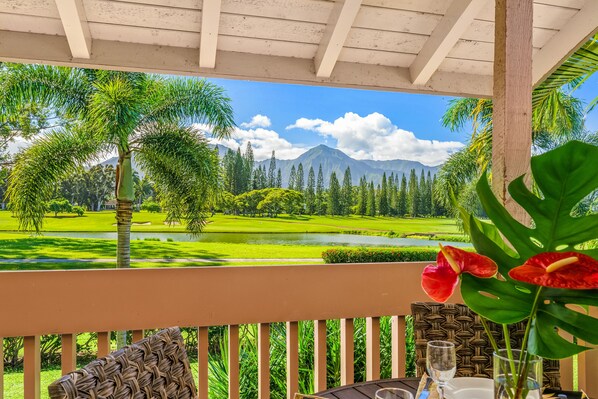 Un espacio al aire libre cubierto con vista a un campo de golf, palmeras y una montaña.