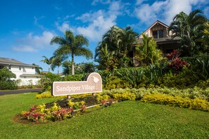 A sign for Sandpiper Village with lush landscaping and a clear blue sky.
