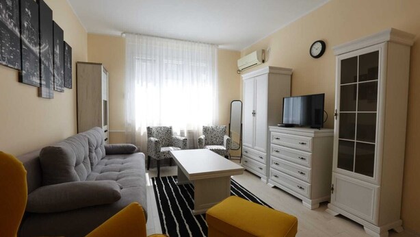 Un salon comprenant un canapé, des fauteuils, une table basse, un téléviseur et une armoire.