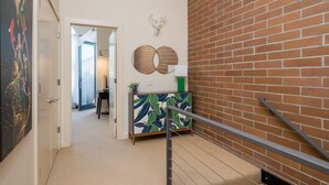 A hallway with a brick wall, a decorative cabinet, and a door leading to another room. - Private Balcony | Firepit | Portable Bar (Ketchum)