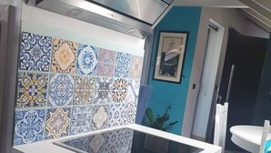 Eine Küche mit modernem Design, mit einer Edelstahl-Dunstabzugshaube, einer gefliesten Spritzschutzwand mit verschiedenen Mustern und einer weißen Arbeitsplatte.